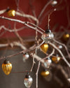 Decorative Christmas baubles hanging on branches against a blurred background