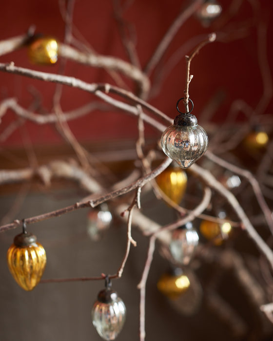 Decorative Christmas baubles hanging on branches against a blurred background