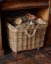Wicker basket with logs inside against a wooden background