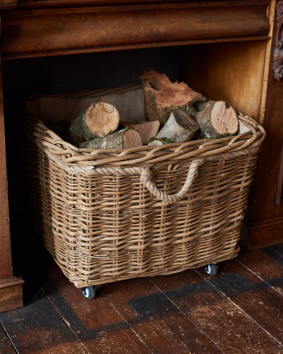 Wicker basket with logs inside against a wooden background