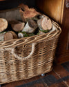 Wicker basket filled with logs on a wooden floor