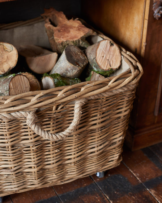 Wicker basket filled with logs on a wooden floor