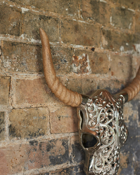 Decorative silver faux bull skull with carved wooden horns.